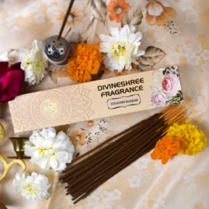 Divineshree Fragrance luxury Sugandh Manjari incense sticks, glowing amidst marigold flowers and puja elements, offering a divine aroma.